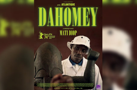 Affiche du film " Dahomey". Personnage principal du film avec un chapeau sur la tête en train de regarder une statue.