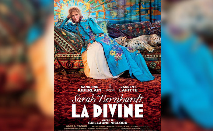 Affiche du film "La divine" avec le personnage principale habillée d'une robe bleue à moitié allongée sur un canapé.