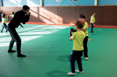 Photo d'enfants en train de faire de la boxe guidés par leur professeur.