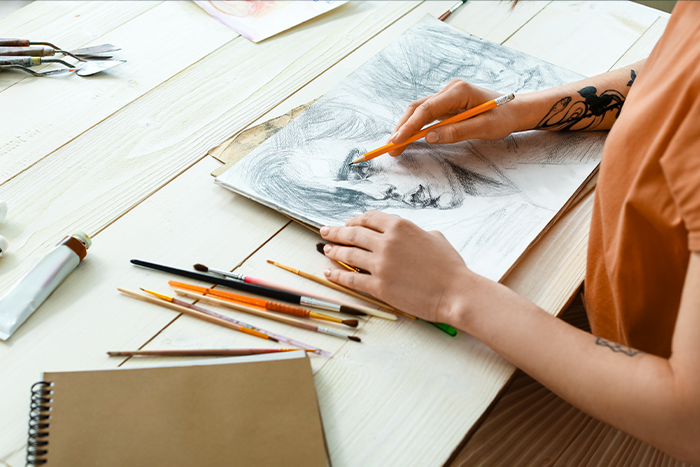 Personne en train de dessiner un visage sur un papier blanc.