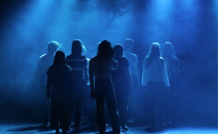 enfants de dos sur une scène en train de jouer une pièce de théâtre